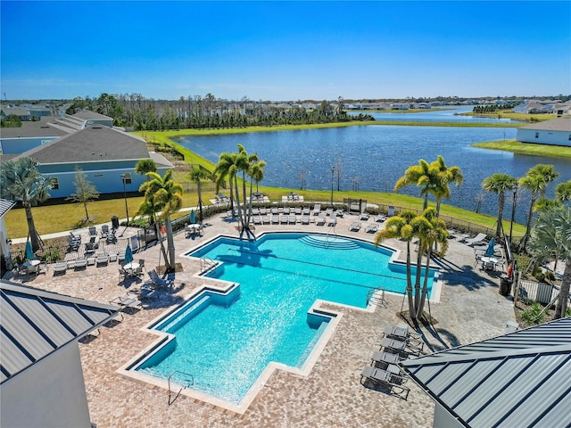 community pool with a water view, a patio, and fence