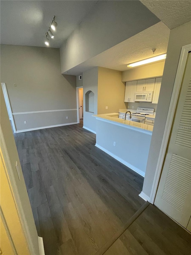 kitchen featuring white appliances, arched walkways, dark wood-style flooring, a textured ceiling, and white cabinetry