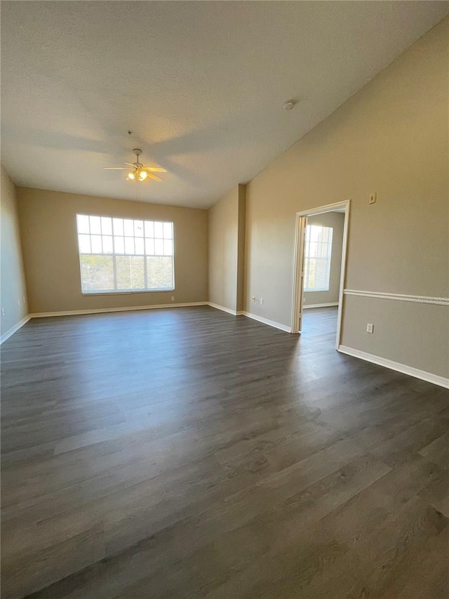 spare room with baseboards, a textured ceiling, dark wood finished floors, and a ceiling fan