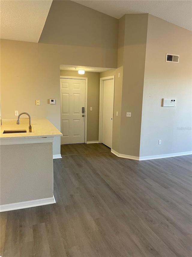 interior space featuring visible vents, a sink, light countertops, baseboards, and dark wood-style flooring