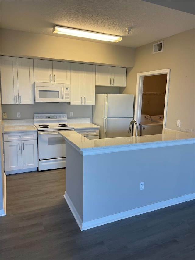 kitchen with washing machine and clothes dryer, visible vents, white appliances, and light countertops