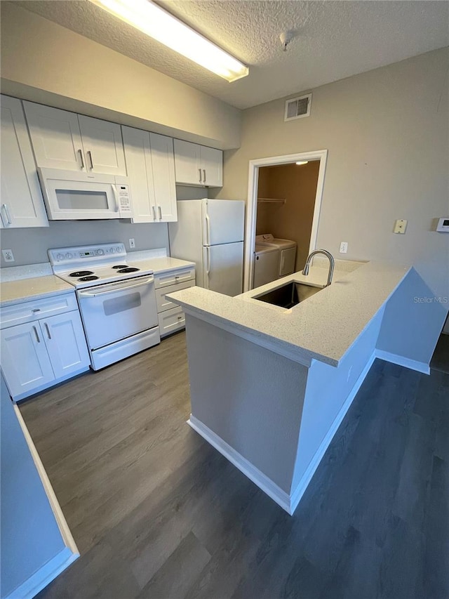 kitchen with visible vents, independent washer and dryer, a sink, white appliances, and white cabinets