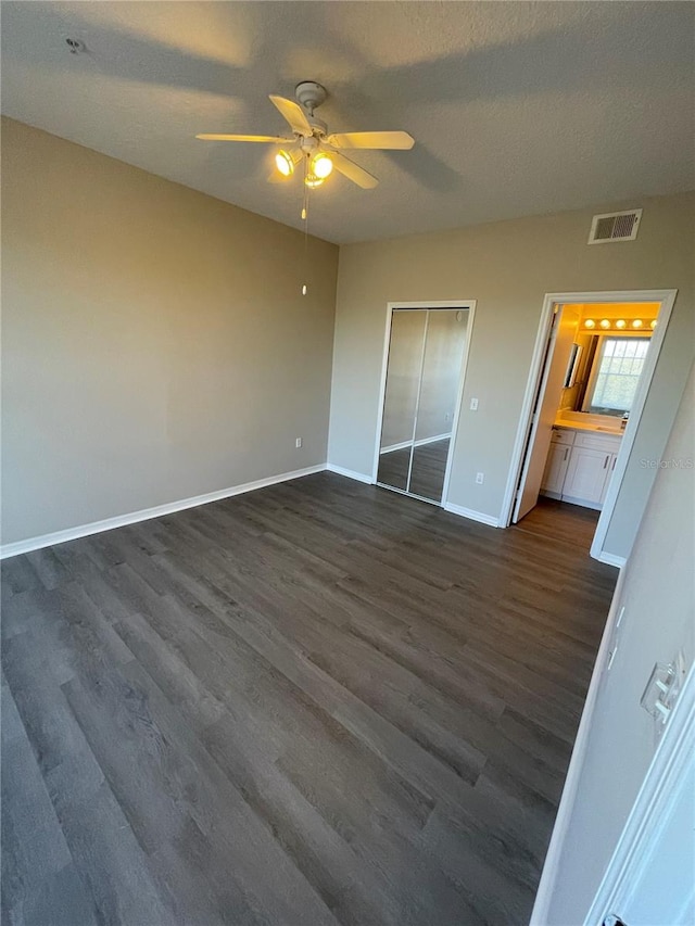 unfurnished bedroom featuring a ceiling fan, dark wood-style floors, visible vents, baseboards, and a textured ceiling