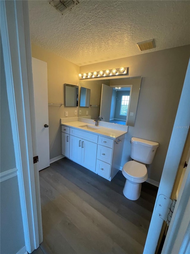 bathroom featuring vanity, wood finished floors, visible vents, and a textured ceiling