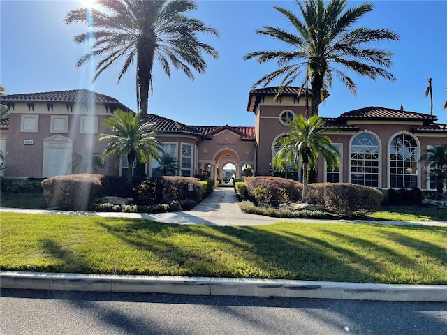 view of front of home featuring stucco siding, a front lawn, and a tiled roof