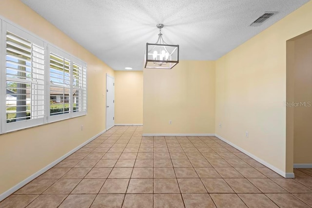 tiled empty room featuring a textured ceiling, baseboards, visible vents, and a chandelier