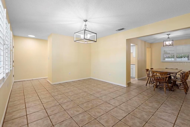 dining space featuring an inviting chandelier, baseboards, visible vents, and a textured ceiling