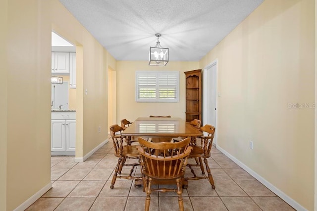 dining space featuring light tile patterned floors, baseboards, a notable chandelier, and a textured ceiling