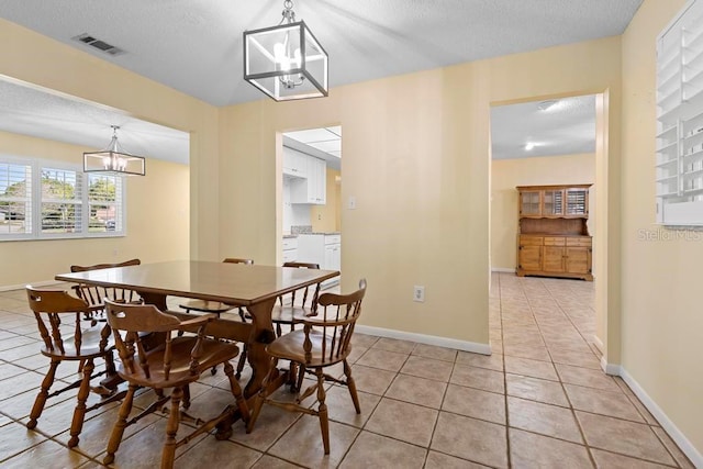 dining room featuring light tile patterned floors, baseboards, visible vents, a textured ceiling, and a chandelier