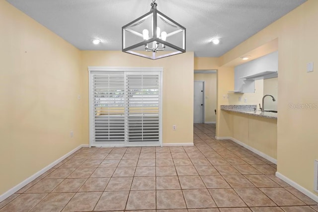 unfurnished dining area with light tile patterned floors, baseboards, a notable chandelier, and a textured ceiling