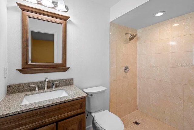 full bath with toilet, vanity, and a tile shower