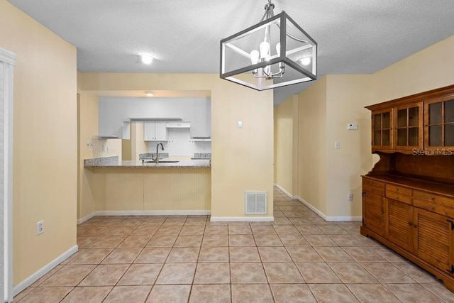 kitchen with visible vents, a chandelier, light tile patterned floors, a textured ceiling, and a sink