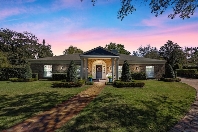 view of front of house with a lawn and brick siding