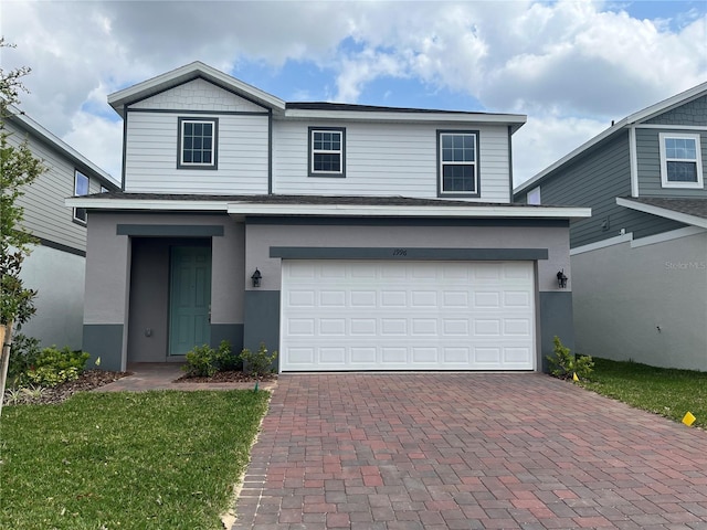 traditional home with decorative driveway, a garage, and stucco siding