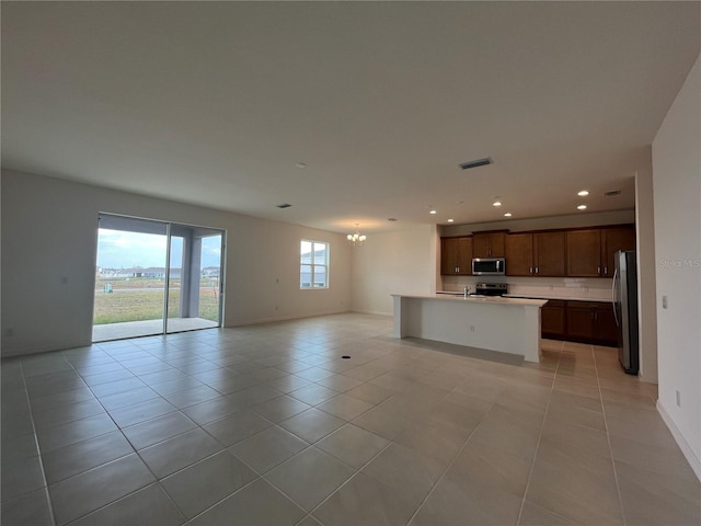 unfurnished living room featuring light tile patterned floors, visible vents, baseboards, an inviting chandelier, and recessed lighting