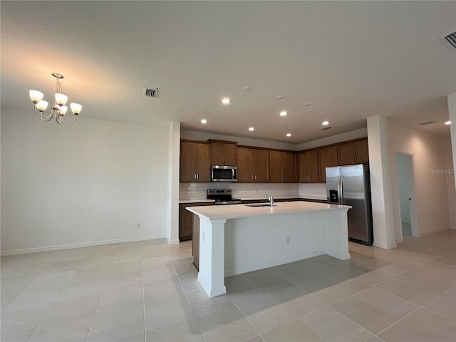 kitchen with visible vents, an island with sink, stainless steel appliances, decorative backsplash, and light countertops