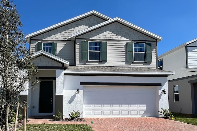 view of front of property with a garage, decorative driveway, a shingled roof, and stucco siding