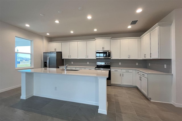 kitchen featuring a center island with sink, a sink, white cabinetry, appliances with stainless steel finishes, and light countertops