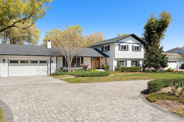 split level home featuring brick siding, an attached garage, concrete driveway, and a chimney