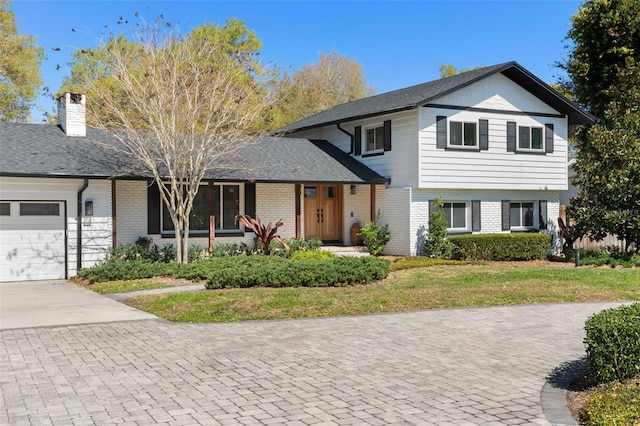 split level home with a garage, brick siding, concrete driveway, and a front lawn