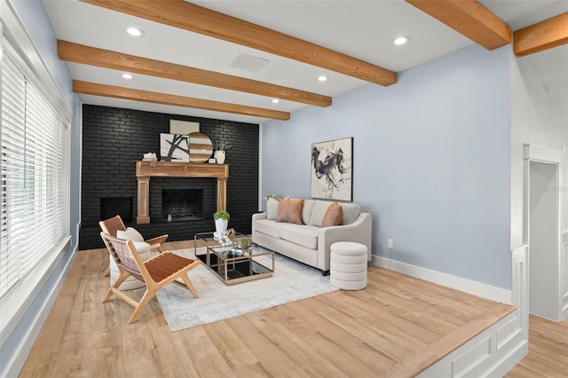 living room with wood finished floors, visible vents, beamed ceiling, baseboards, and a brick fireplace