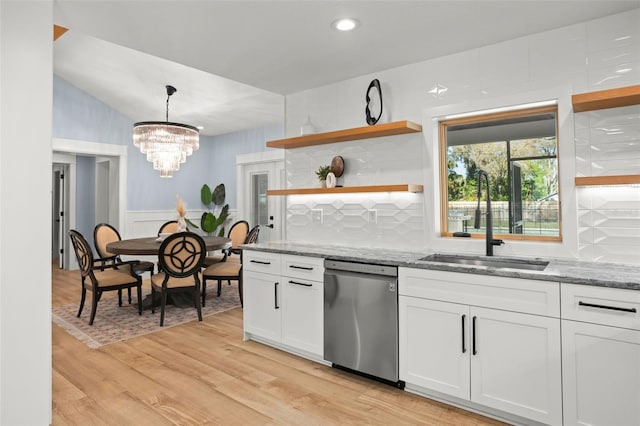 kitchen with light stone counters, light wood-type flooring, stainless steel dishwasher, and white cabinets