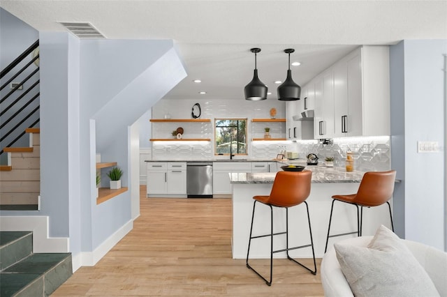 bar featuring visible vents, decorative backsplash, under cabinet range hood, dishwasher, and light wood-type flooring