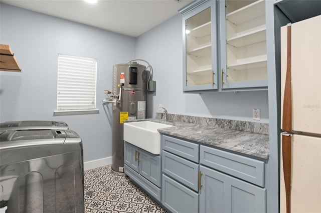 laundry room featuring baseboards, cabinet space, water heater, a sink, and washer and clothes dryer