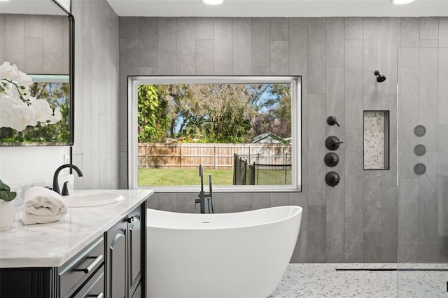 bathroom with a tile shower, a freestanding bath, and vanity