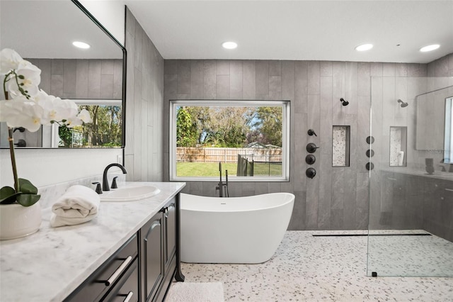 full bathroom with a healthy amount of sunlight, vanity, walk in shower, and a freestanding tub