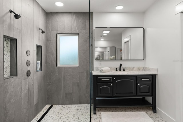 bathroom with vanity, baseboards, and tiled shower