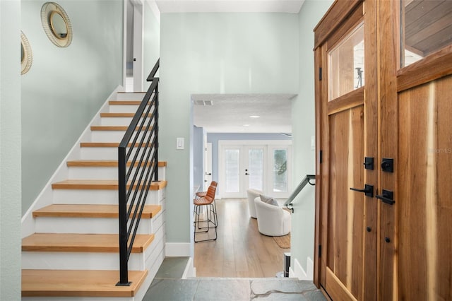 foyer entrance featuring stairway, wood finished floors, baseboards, visible vents, and french doors