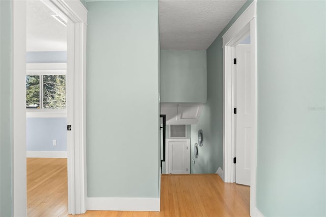 corridor featuring visible vents, baseboards, a textured ceiling, and wood finished floors