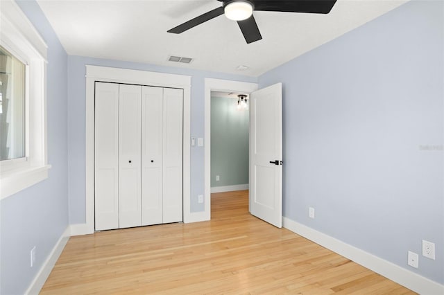 unfurnished bedroom featuring visible vents, a ceiling fan, wood finished floors, a closet, and baseboards