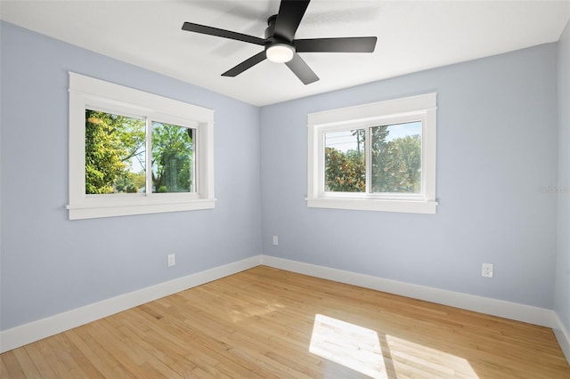 spare room with light wood-style flooring, plenty of natural light, a ceiling fan, and baseboards