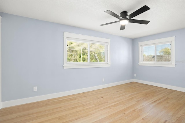 empty room featuring baseboards, light wood-type flooring, a wealth of natural light, and ceiling fan