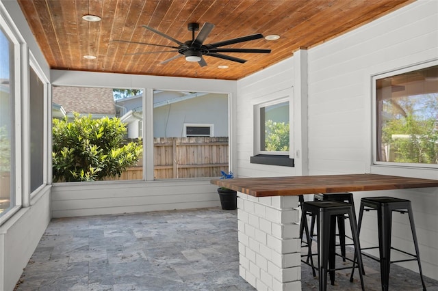 unfurnished sunroom with a ceiling fan and wood ceiling