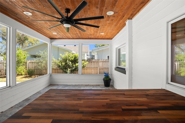 unfurnished sunroom featuring a ceiling fan, wood ceiling, and a healthy amount of sunlight