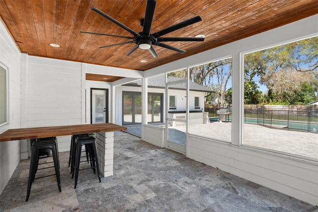 unfurnished sunroom featuring wood ceiling and ceiling fan