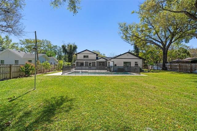 rear view of property featuring a fenced in pool, a fenced backyard, and a lawn