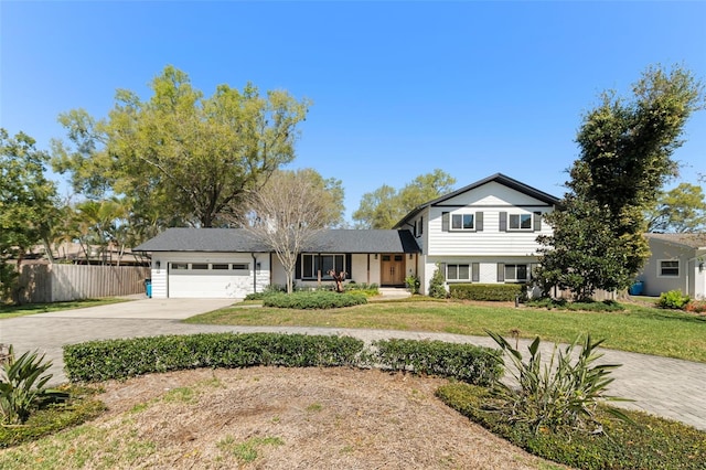 split level home with driveway, a front yard, a garage, and fence