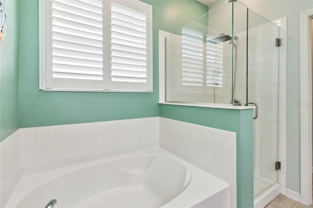 full bathroom featuring tile patterned flooring, a garden tub, and a stall shower