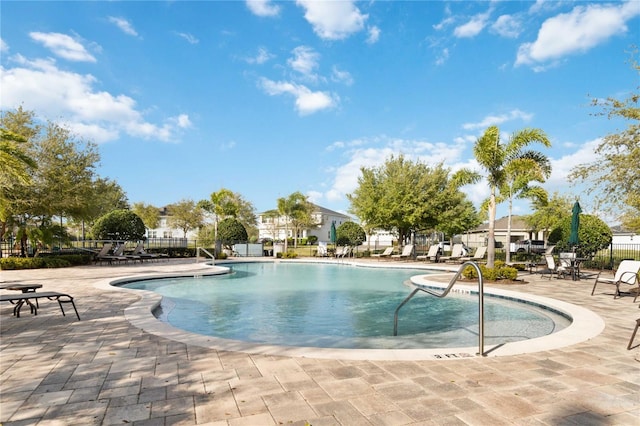 community pool with a patio area and fence