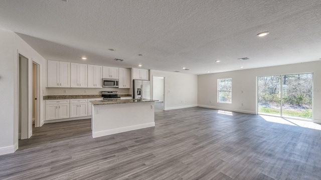 5963 Virtudes St, Sebring, FL 33872 - kitchen featuring stainless steel appliances, baseboards, white cabinets, a textured ceiling, and a kitchen island