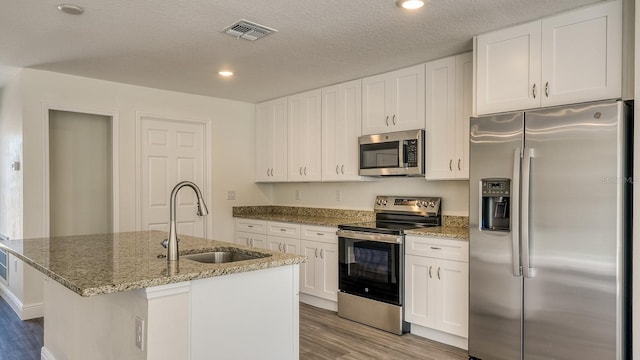 5963 Virtudes St, Sebring, FL 33872 - kitchen with appliances with stainless steel finishes, a sink, wood finished floors, white cabinets, and stone counters