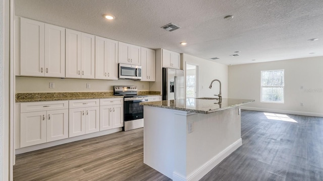 5963 Virtudes St, Sebring, FL 33872 - kitchen with appliances with stainless steel finishes, a sink, wood finished floors, white cabinetry, and a textured ceiling
