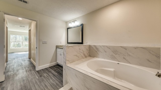 5963 Virtudes St, Sebring, FL 33872 - bathroom featuring a textured ceiling, vanity, a garden tub, wood finished floors, and baseboards