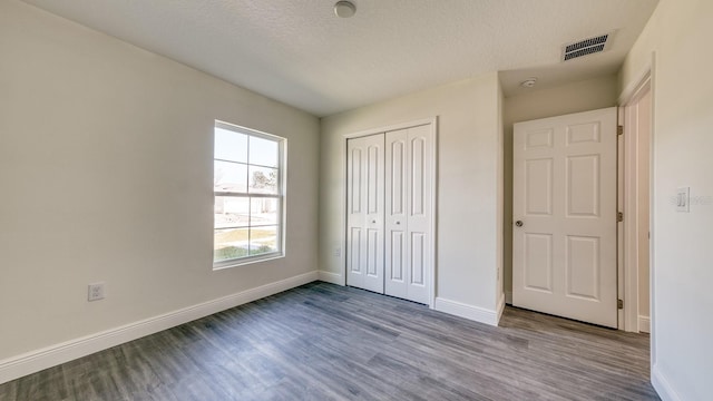 5963 Virtudes St, Sebring, FL 33872 - unfurnished bedroom with wood finished floors, baseboards, a closet, and a textured ceiling