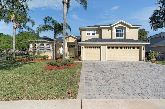 view of front facade with a garage, decorative driveway, a front yard, and stucco siding