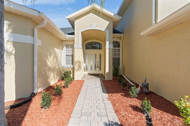 property entrance featuring stucco siding and french doors